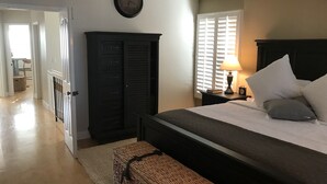 A bedroom with a bed, a nightstand, a lamp, a clock on the wall, and a wardrobe.