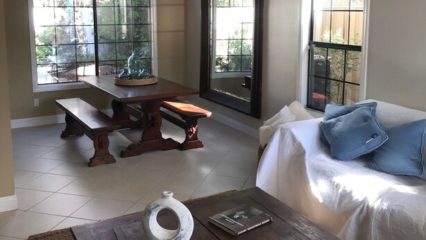 A spacious living area with a large dining table, a sofa with blue cushions, and a coffee table with a chalkboard.