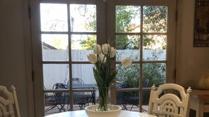 A dining area with a round table, white chairs, and a vase of white flowers.