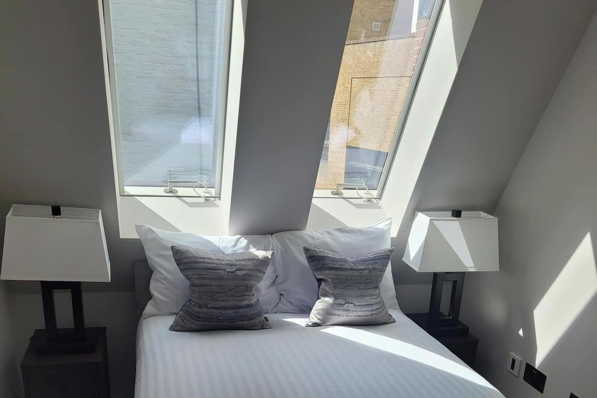 Une chambre avec un grand lit, deux lampes de chevet, une fenêtre et une serviette sur le lit.