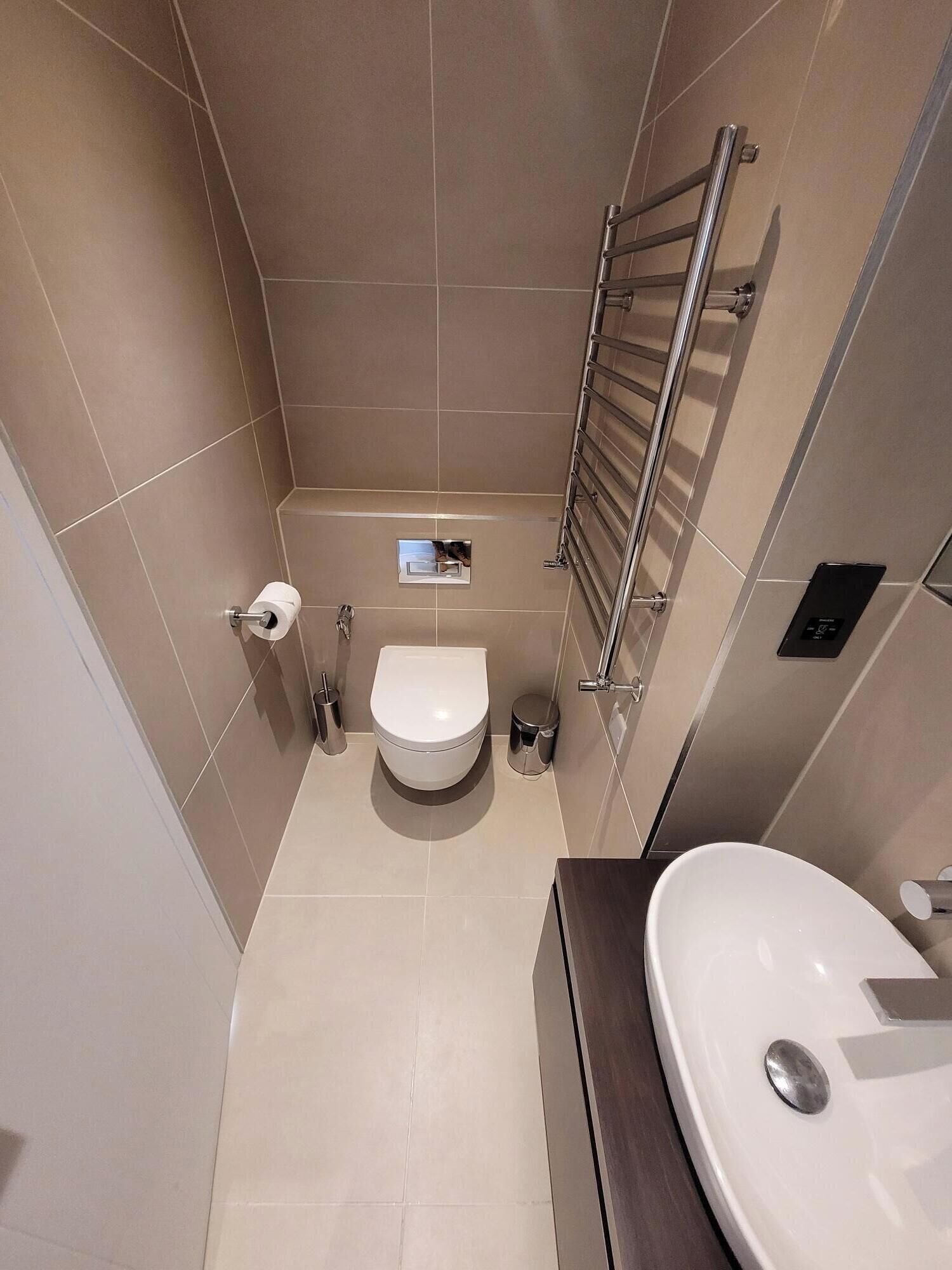 Un baño moderno y compacto con inodoro, bidé y lavamanos.