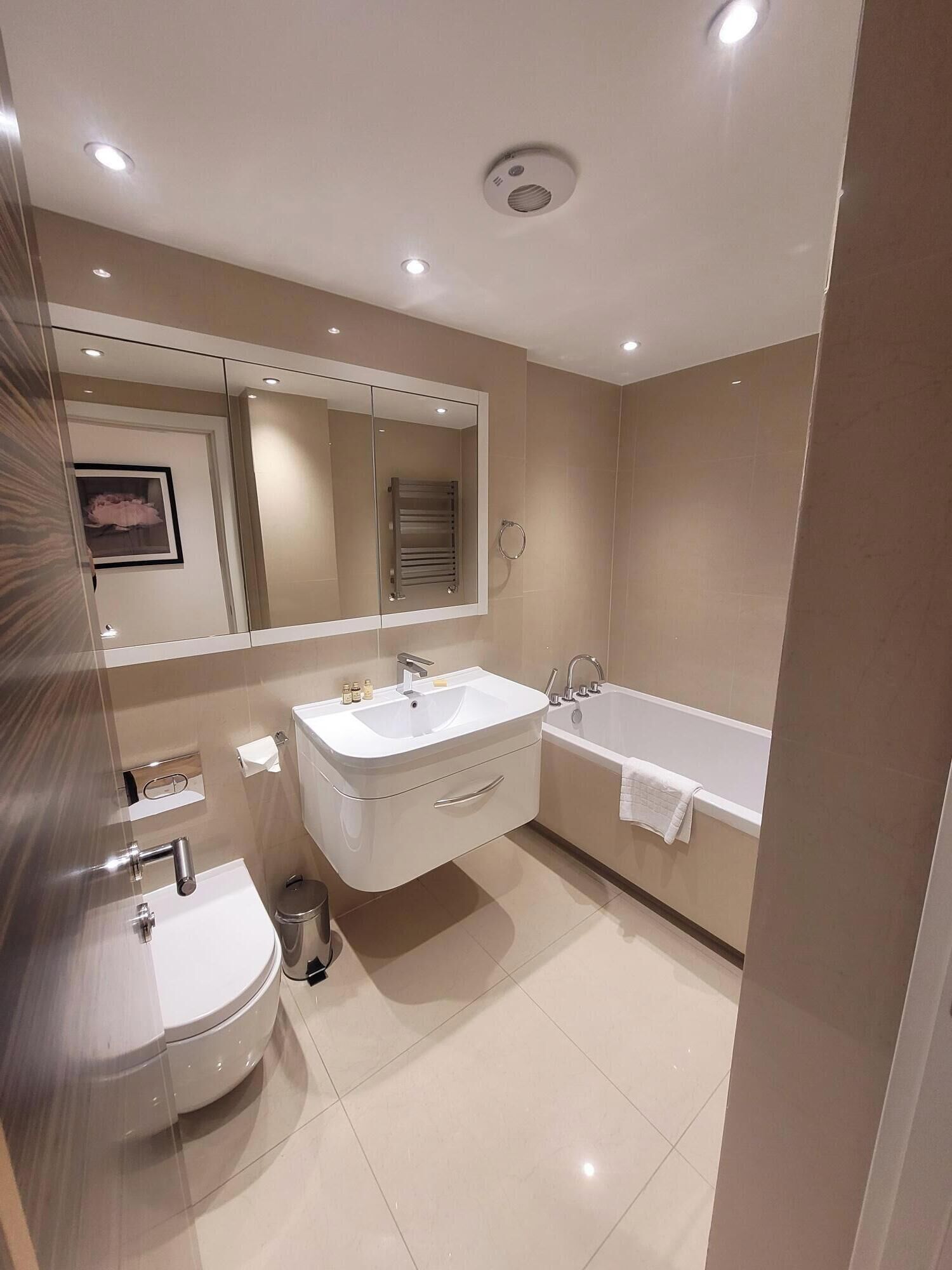 A modern bathroom with a sink, mirror, and bathtub.