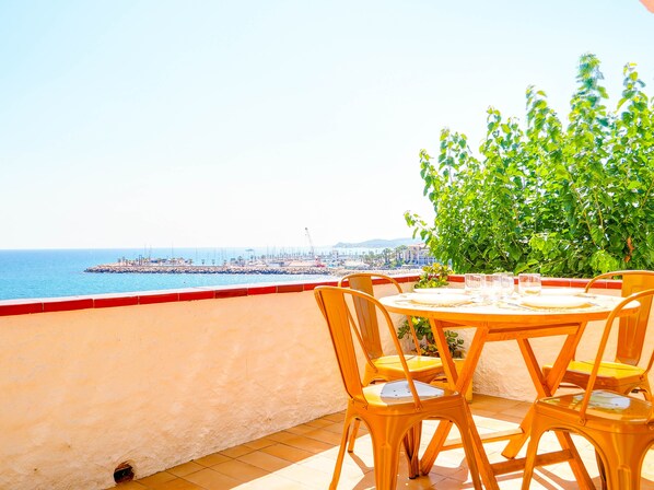Une terrasse avec une table et des chaises donnant sur une vue sur la côte.