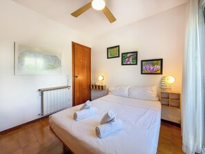 Quarto de hotel com uma cama, porta de madeira, radiador e obras de arte penduradas na parede.