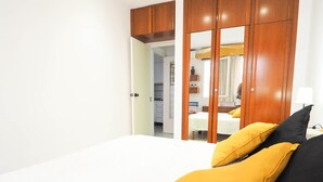 A bedroom with a bed, a wardrobe, and a mirror. - Sunflower Apartment by Hello Homes Sitges (Sitges)