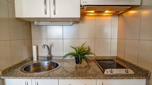 A kitchen with a stainless steel sink, a built-in stove, and white cabinets. - The Blue Island Loft by Hello Homes Sitges (Sitges)