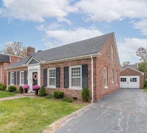 A two-story brick house with a garage, a front porch with potted plants, and a well-maintained lawn. - Chevy Chase-1mi to Rupp-Kroger Field-Downtown (Lexington)