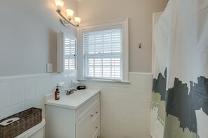 A bathroom with white tiles, a sink with a mirror, a window with blinds, and a shower curtain. - Chevy Chase-1mi to Rupp-Kroger Field-Downtown (Lexington)