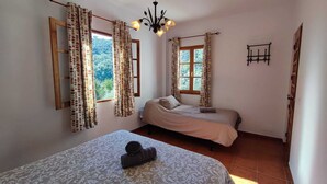 Une chambre avec deux lits, un lustre et des rideaux.