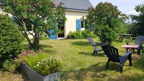 Un jardí amb una casa, seients exteriors i taula de pícnic.