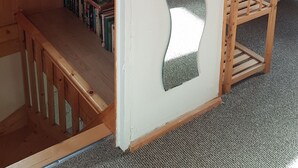 Un interior de fusta amb una porta de disseny singular, oniu, i una estanteria plena de llibres, a més d'una cadira de fusta.