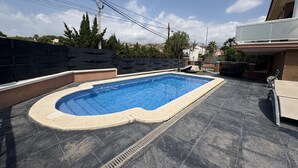 A rectangular swimming pool with a tiled deck surrounding it.