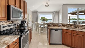 A modern kitchen with wooden cabinets, stainless steel appliances, and a view of a lake.