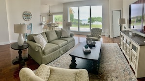 A spacious living room with a sofa, armchairs, a coffee table, and a TV.