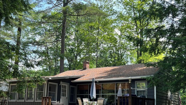 A single-story house with a porch, a covered outdoor seating area, and a small deck.