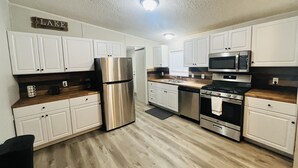 Una cocina moderna con armarios blancos, electrodomésticos de acero inoxidable y encimera de madera.