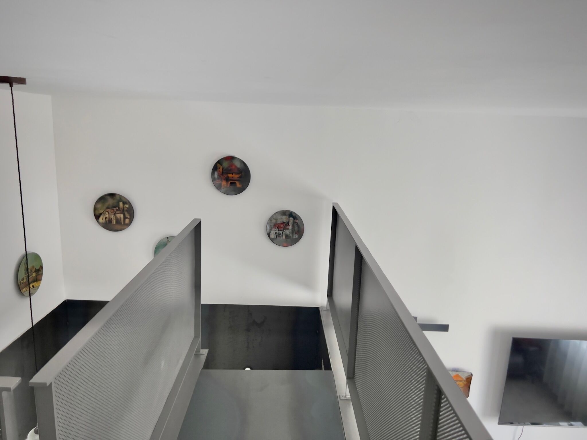 A modern office space with metal partitions, a white wall, and three circular artwork pieces.