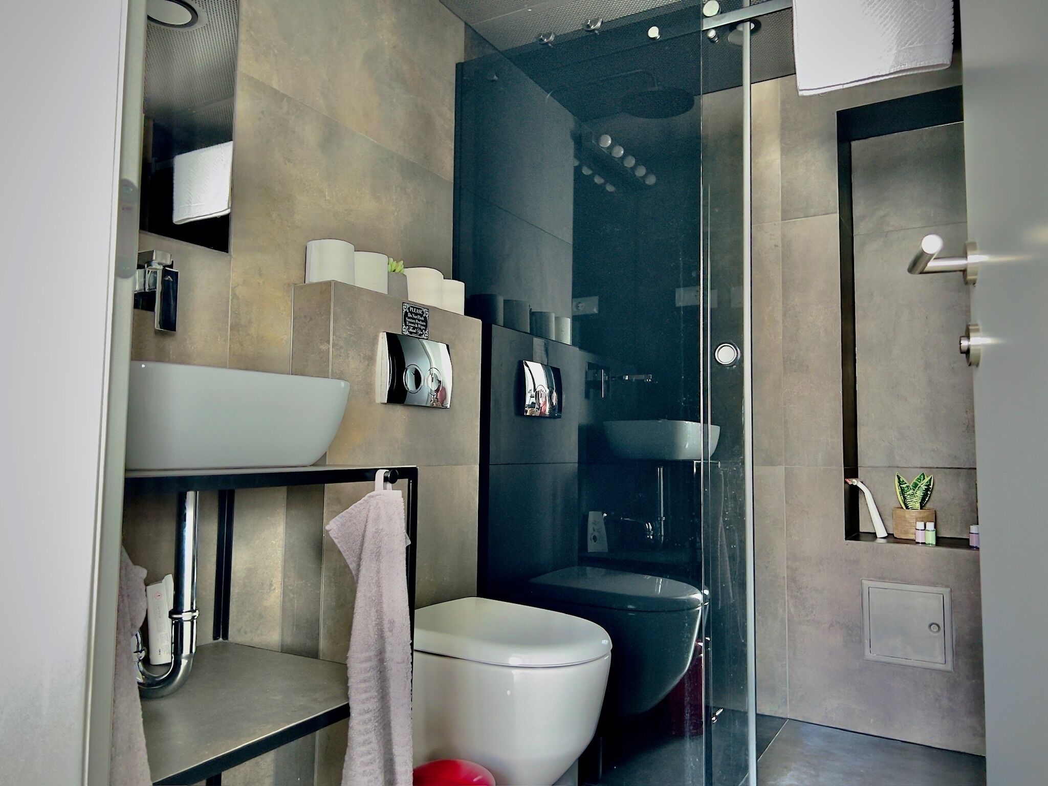 Un baño moderno con un lavamanos grande, inodoro y cabina de ducha con mampara de vidrio.