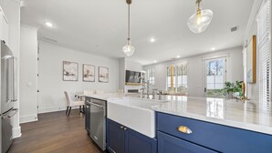 Een moderne keuken met een groot eiland, witte kastjes en een roestvrijstalen koelkast.