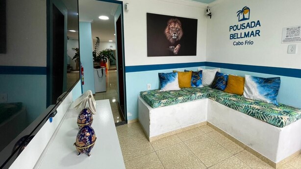 A reception area with a sofa, a mirror, and a wall-mounted sign. - Pousada BellMar (Cabo Frio)