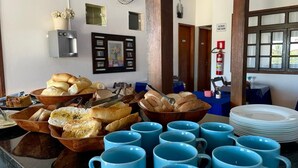 Un buffet de petit-déjeuner avec du pain, des viennoiseries et des tasses bleues.
