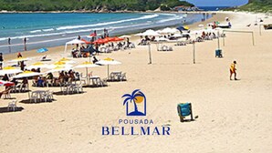 A beach scene with the text "PRAIA DO PERÓ" and "POUSADA BELLMAR" indicating a beach resort. - Pousada BellMar (Cabo Frio)