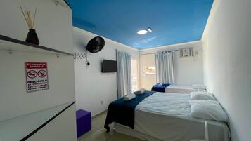 Habitación de hotel con cama, televisión, ventilador de techo y un cartel sobre el ahorro de energía.
