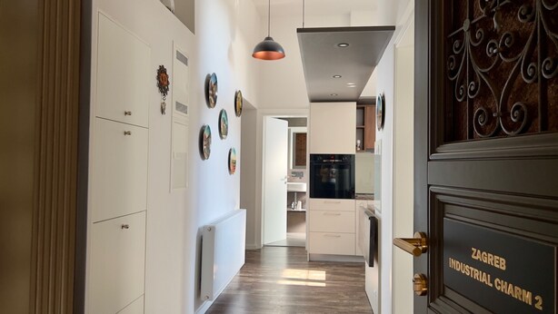 Eine moderne Küche mit weißen Schränken, einem schwarzen Kühlschrank und einer dekorativen Metalttür.