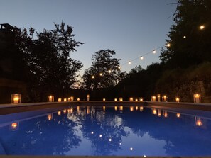 A swimming pool at dusk with string lights and candles around it. - Romantic villa in the Dordogne, air-conditioned, private heated pool, king-size bed (Les Eyzies)
