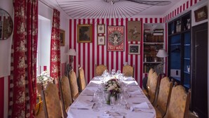 Ein Esszimmer mit langem Tisch, gedeckten Plätzen, Streifenmuster an den Wänden und einer Deckenleuchte.