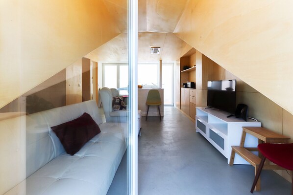 A compact living space with a sofa, a television, and a dining area. - Belem Experience III by Homing (Lisbon)