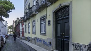 A narrow cobblestone street with buildings on either side, featuring a mix of residential and commercial properties. - Chiado Prime Suites I by Homing (Lisbon)