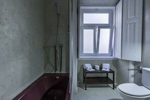 Une salle de bain avec une baignoire, des toilettes et une fenêtre.