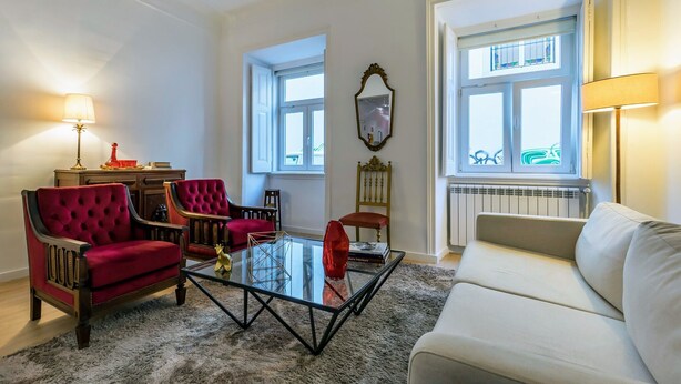 A living room with a glass coffee table, red and white sofas, and a radiator. - Chiado Prime Suites I by Homing (Lisbon)