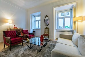 Un salon avec une table basse en verre, des canapés rouges et blancs, et un radiateur.