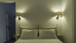 A bed with a headboard, two bedside lamps, and a nightstand. - Chiado Prime Suites I by Homing (Lisbon)