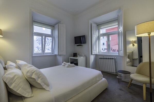 Une chambre d’hôtel avec un lit, une télévision, une chaise et une lampe.