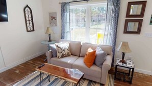 Un salon avec un canapé, une table basse, une lampe et une fenêtre avec des rideaux.