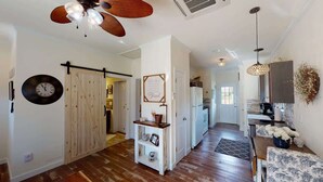 Une cuisine spacieuse avec un plancher en bois, un ventilateur de plafond et un coin repas comprenant une table et des chaises.