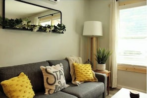 Relax in this inviting living room with a sofa, mirror, and floor lamp.