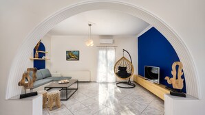 Uma sala de estar moderna com sofá, mesa de centro, cadeira suspensa e televisão.
