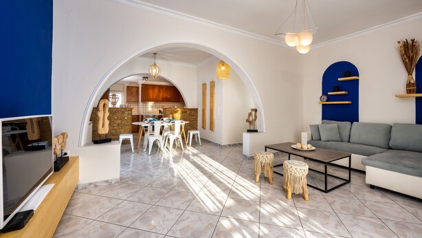 Uma sala de estar ampla com cozinha moderna, área de refeições e espaço de estar com sofá e mesa de centro.