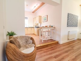 Una cocina moderna con armarios de madera, encimera blanca y una pequeña barra con taburetes.