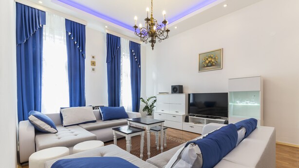 A modern living room with a sofa set, a TV, and a chandelier.