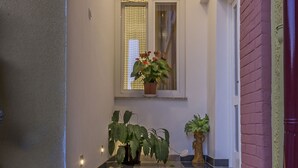 A modern hotel entrance with a marble staircase, potted plants, and a small window with a view.