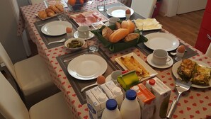 A breakfast table with various food items, plates, cups, and milk cartons.