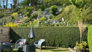 A well-maintained garden with a seating area featuring plastic chairs and a table, surrounded by neatly trimmed hedges and a variety of plants. - COTE D'ALBÂTRE BEACH 5 MINUTES AWAY (Criel-sur-Mer)