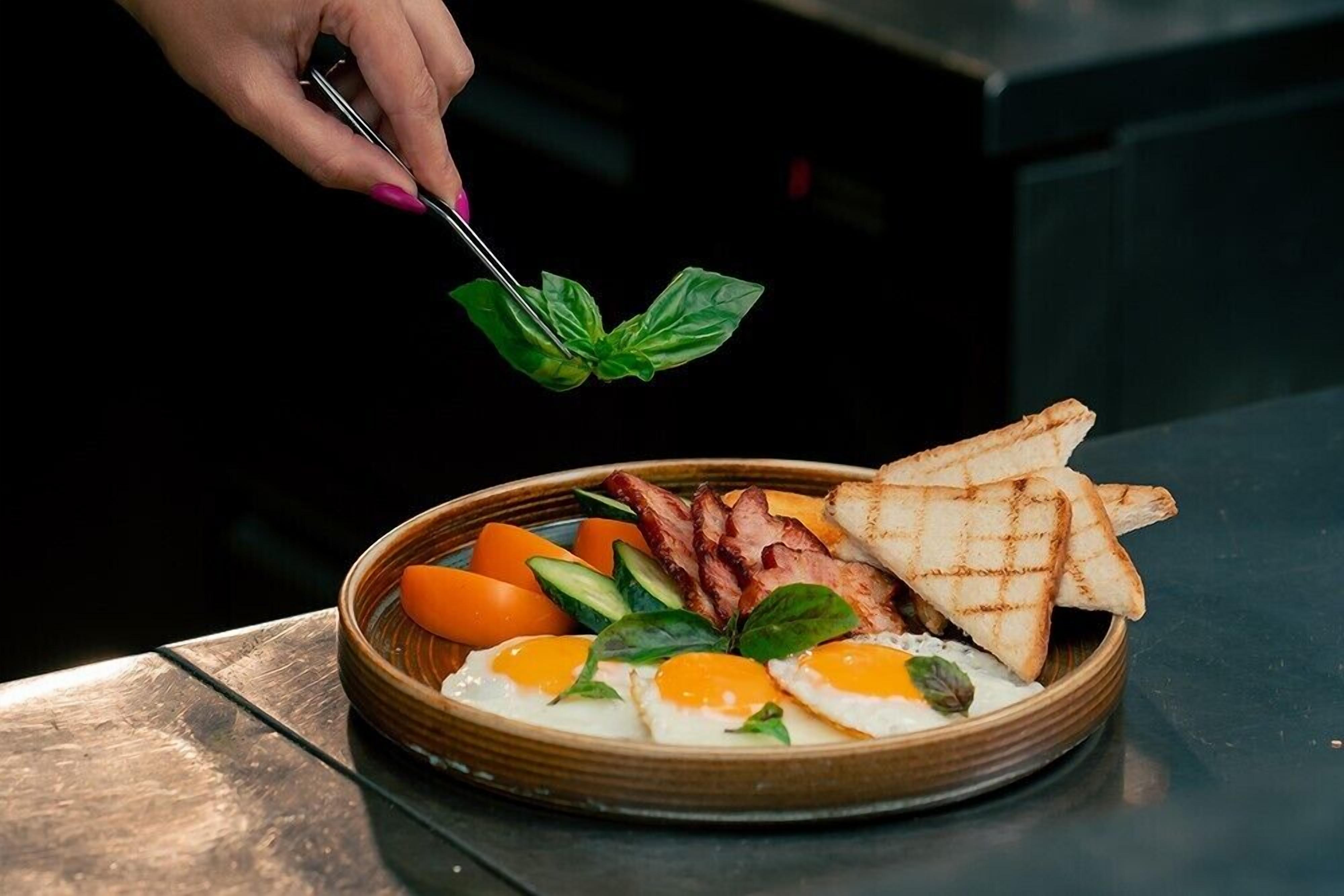 Ein Frühstücksteller mit Eiern, Speck, Toast und Gemüse.