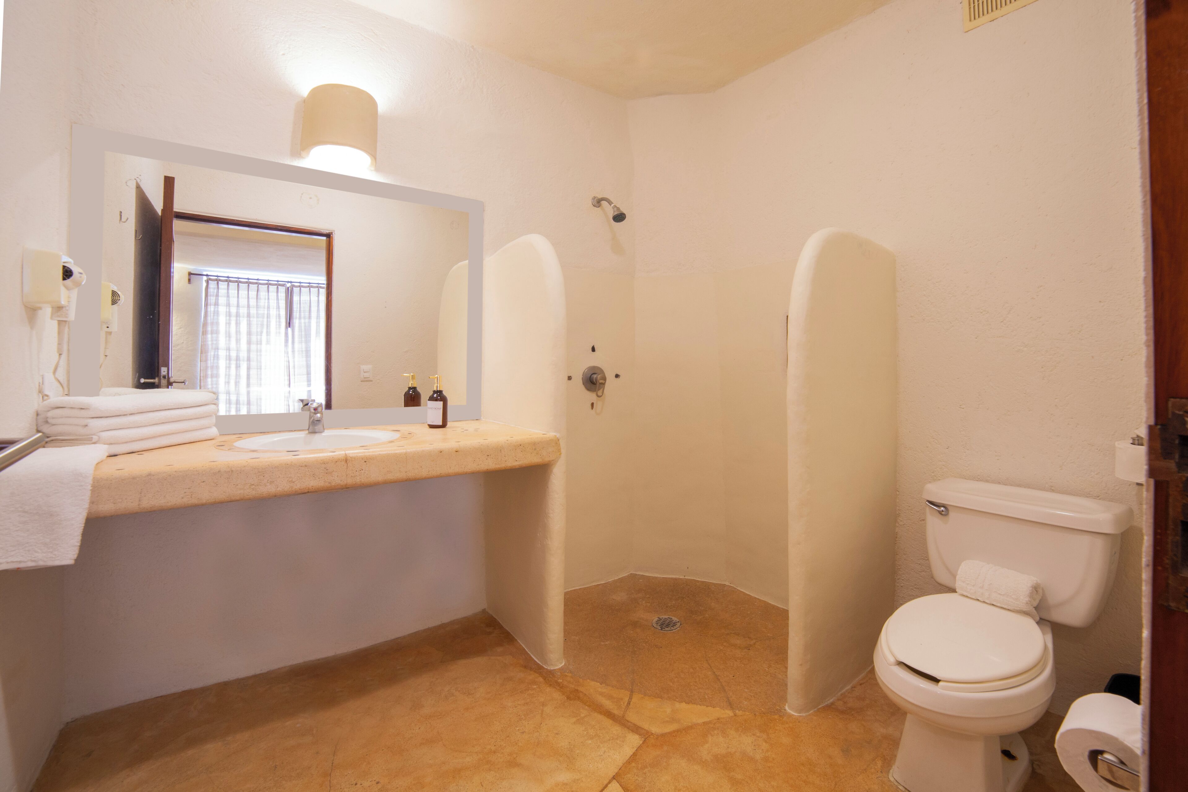 A bathroom with a sink, mirror, toilet, and shower stall.