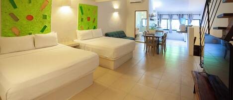 A hotel room with two beds, a dining area, and a staircase.
